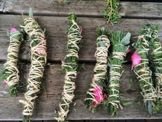 several bundles of flowers are tied together on a wooden table with grass and pink flowers