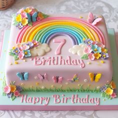 a birthday cake decorated with butterflies, flowers and a rainbow on the top that says happy birthday