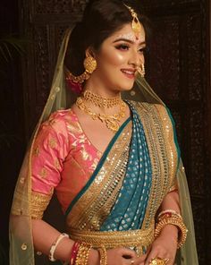 a woman in a blue and gold sari with jewelry on her neck, standing next to a doorway