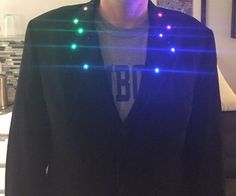 a man standing in front of a couch wearing glasses and a jacket with lights on it