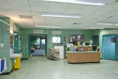 an empty hospital room with green walls and white ceiling tiles on the floor is shown