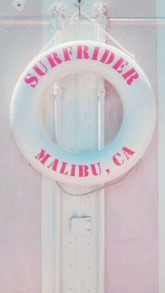 a life preserver on the side of a building with pink lettering that says surf rider malbu, ca