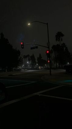 an intersection at night with traffic lights and palm trees