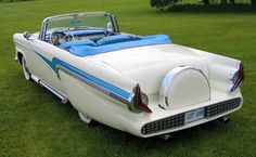 an old white car parked in the grass