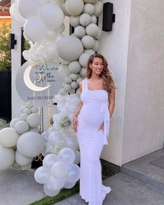 a pregnant woman standing in front of balloons