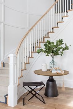 there is a vase with flowers on the table next to the stairs in this house