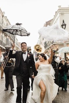 a bride and groom walking down the street holding umbrellas