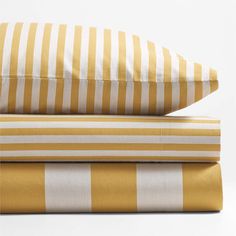 three pillows stacked on top of each other with yellow and white striped sheets in the background