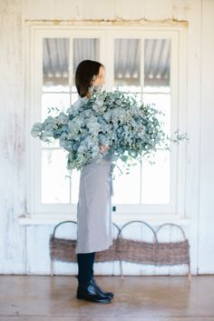 a woman holding a bouquet of flowers in front of a window