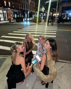 four women sitting on the ground talking to each other in front of a crosswalk