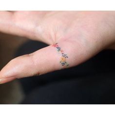 a person's hand with a small flower tattoo on their left thumb and finger