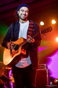 a man holding an acoustic guitar on stage