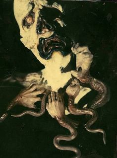 an image of a creepy man with snakes on his face and hands in the air