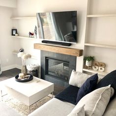 a living room with white furniture and a flat screen tv mounted above the fire place