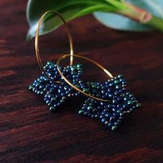 a pair of gold hoop earrings with blue beading on top of a wooden table