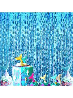 there is a cake with mermaid decorations on it and under the water streamers behind it