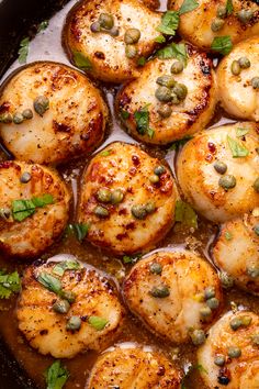 a pan filled with cooked scallops and garnished with capers on top