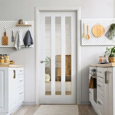 a white door in a kitchen next to a counter and cabinets with utensils hanging on the wall