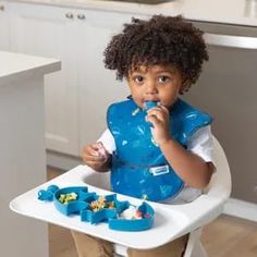 a little boy sitting in a high chair eating food