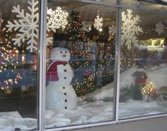 a snowman sitting in front of a store window