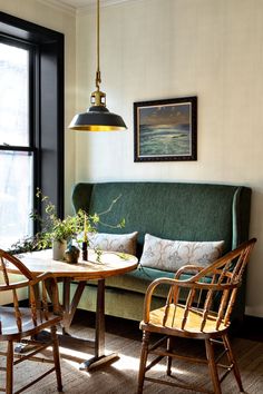 a green couch sitting next to a table with two chairs and a potted plant