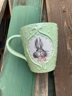 a green coffee cup with an image of a rabbit on it