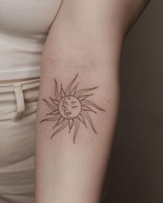 a woman's arm with a small sun and moon tattoo on the left side