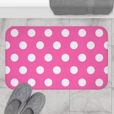 a bathroom rug with white polka dots on it and two pairs of gray slippers