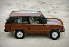 a brown car parked on top of a sandy beach