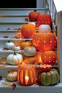 pumpkins and gourds are sitting on the steps in front of stairs with candles