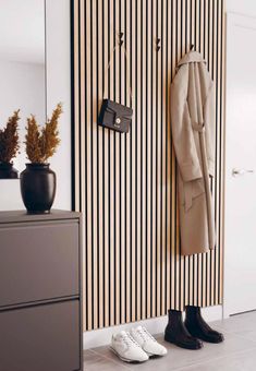 a pair of shoes is sitting on the floor in front of a coat rack and striped wall