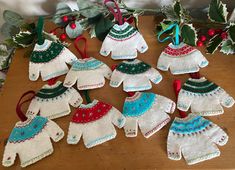 knitted mittens and gloves hanging on a table next to holly branches with scissors