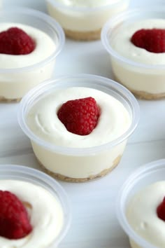 small desserts with white frosting and raspberries in plastic containers on a table