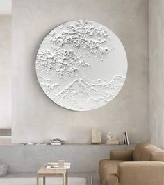 a living room filled with furniture and a large white circular wall art hanging on the wall