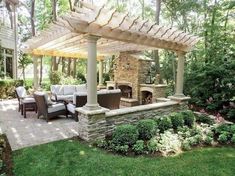 an outdoor living area with stone fireplace and patio furniture