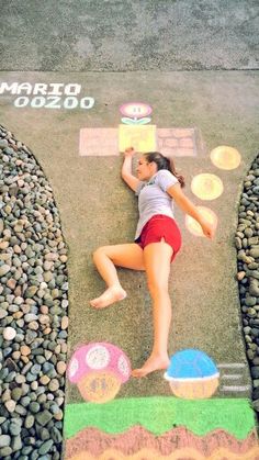 a woman laying on top of a sidewalk next to some rocks and stones with words painted on it