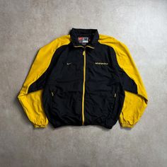 Size: M Fits like a: M Condition: Excellent * Vintage 90's Nike Mizzou jacket with iconic design and sporty flair. Measurements (cm): Chest: 64 cm Length: 71 cm Shoulders: 56 cm Arms: 64 cm *Please note that all garments are vintage or second-hand and show signs of wear. We carefully examine the condition of the garment to price our products. Returns or exchanges are not accepted, all sales are final. #NikeJacket #VintageNike #RetroStyle #SportsFashion #90sFashion Urban Style Track Jacket For Sports, Sporty Winter Outerwear With Logo Detail, Sporty Long Sleeve Varsity Jacket With Logo, Sporty Varsity Jacket With Logo Detail For Fall, Sporty Fall Varsity Jacket With Logo Detail, Throwback Long Sleeve Track Jacket For Sports Events, Black Logo Detail Outerwear For Streetwear, Casual Winter Varsity Jacket With Logo Detail, Sporty Streetwear Varsity Jacket With Logo