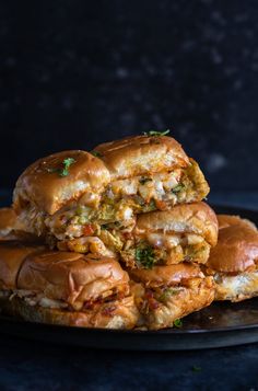 three sandwiches stacked on top of each other on a black plate with one sandwich cut in half