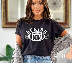 a woman wearing a senior mom t - shirt in front of a mirror with her hands on her hips