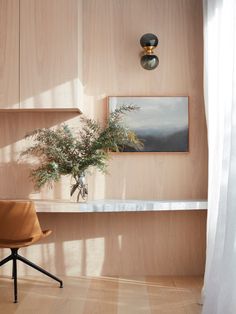 a chair sitting in front of a window next to a potted plant on top of a table