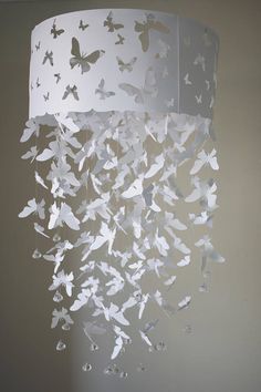 a white chandelier with paper butterflies hanging from it's sides, in a room