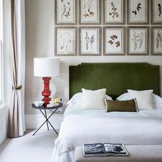 a green headboard in a bedroom with pictures on the wall above it and a lamp next to it