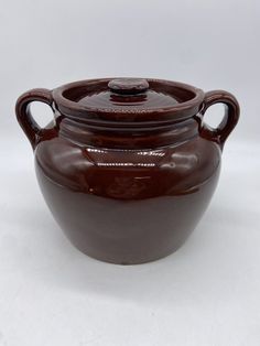 a brown ceramic jar with handles on a white background