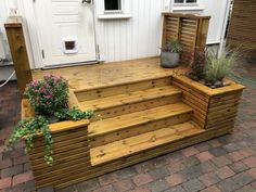 a wooden deck with planters on it and steps leading up to the front door