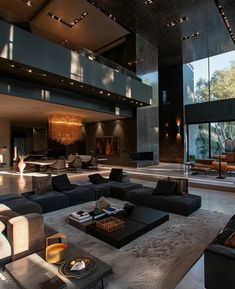 a large living room with couches and tables in front of glass walls that look out onto the outdoors