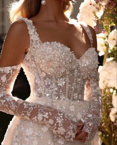 a woman in a wedding dress with long sleeves and flowers on her head is looking off to the side