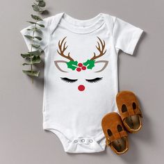 Baby's Christmas gift - Baby's first Christmas gift - Christmas baby outfit - Baby's Christmas outfit - Christmas bodysuit These beautiful reindeer face body suits are idea for your babies first Christmas or to give as a gift for the new baby. Such a lovely item to add to their memory box to treasure forever. The design's feature's the face of a reindeer with a sprig of holly and berries featuring centre in a pearlescent colour.  The baby grow's themselves are made from 100% cotton. The choice of baby grow colour is white, black, red, grey, pale pink or pale blue. With a huge range of colours available for the wording you are sure to find something you will love, these make the idea gift for new parents. Cute Christmas Holiday Onesie, White Cotton Onesie For Holidays, Holiday White Cotton Onesie, Cute White Bodysuit For Winter, Cute Christmas Cotton Onesie, Cute Cotton Christmas Onesie, Cute Christmas Onesie, White Holiday Onesie For Winter, White Winter Holiday Onesie