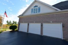 a brick house with two garages and an american flag