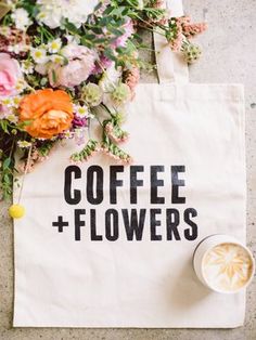 a coffee and flowers tote bag sitting on the ground next to a cup of coffee