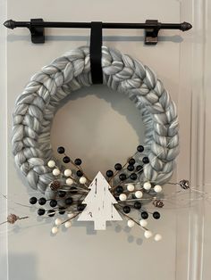 a white wreath with black and white decorations hanging on the front door, next to an arrow